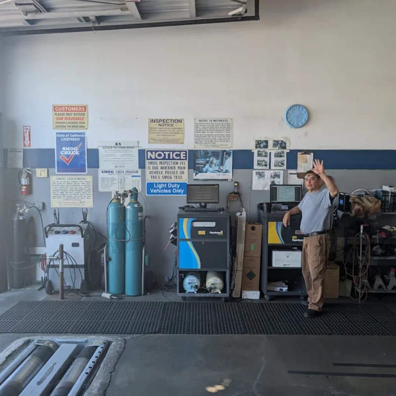 Technician performing a smog inspection on a vehicle connected to diagnostic equipment inside a clean STAR certified smog check station in Southern California.