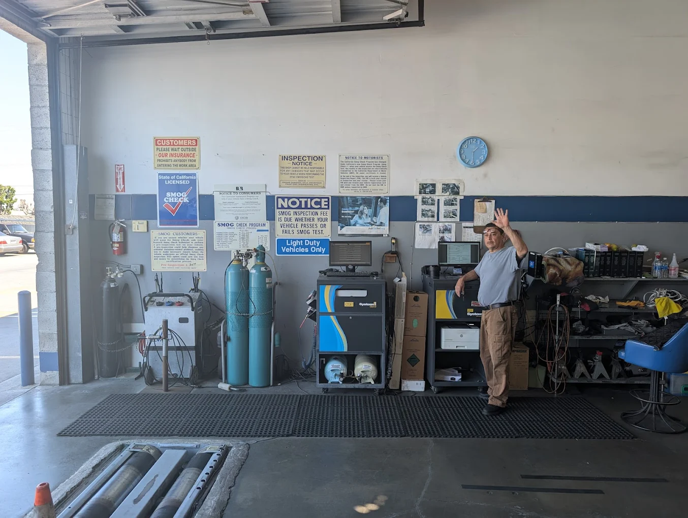 Technician performing a smog inspection on a vehicle connected to diagnostic equipment inside a clean STAR certified smog check station in Southern California.